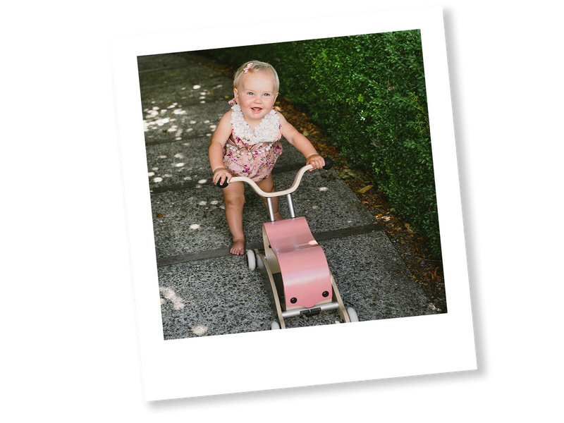 little girl walking assisted with a pink and black mini-flip walker